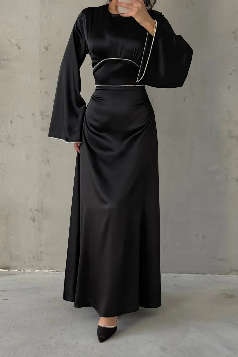 Black maxi dress with wide, flowing sleeves and contrasting white trim along the neckline, waist, and cuffs. The dress is made of a smooth, draping fabric.