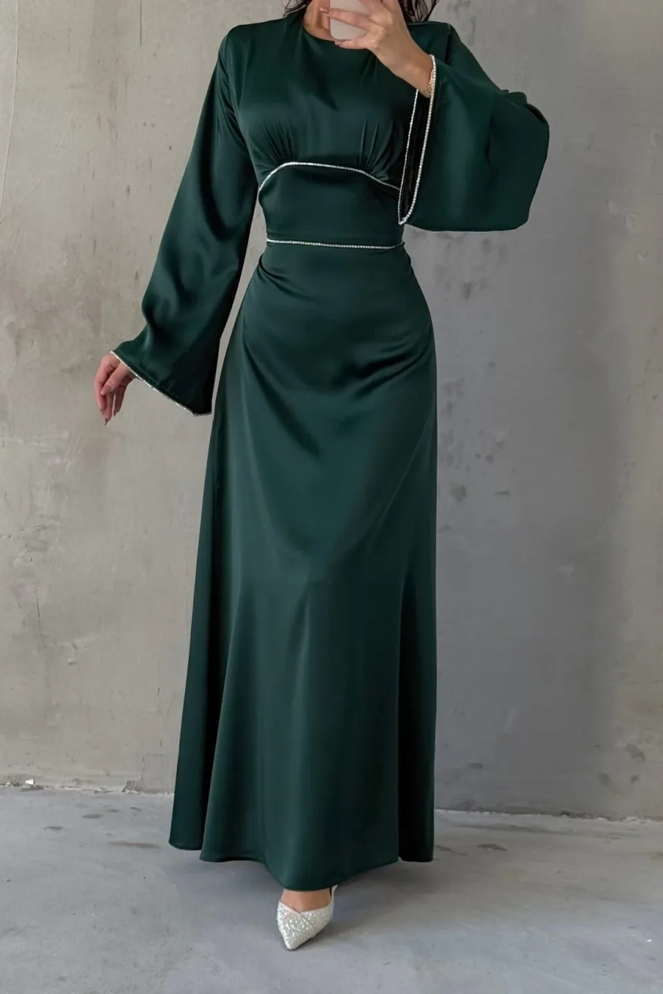 Emerald green maxi dress with wide, flowing sleeves and contrasting white trim along the neckline, waist, and cuffs. The dress is made of a smooth, draping fabric.