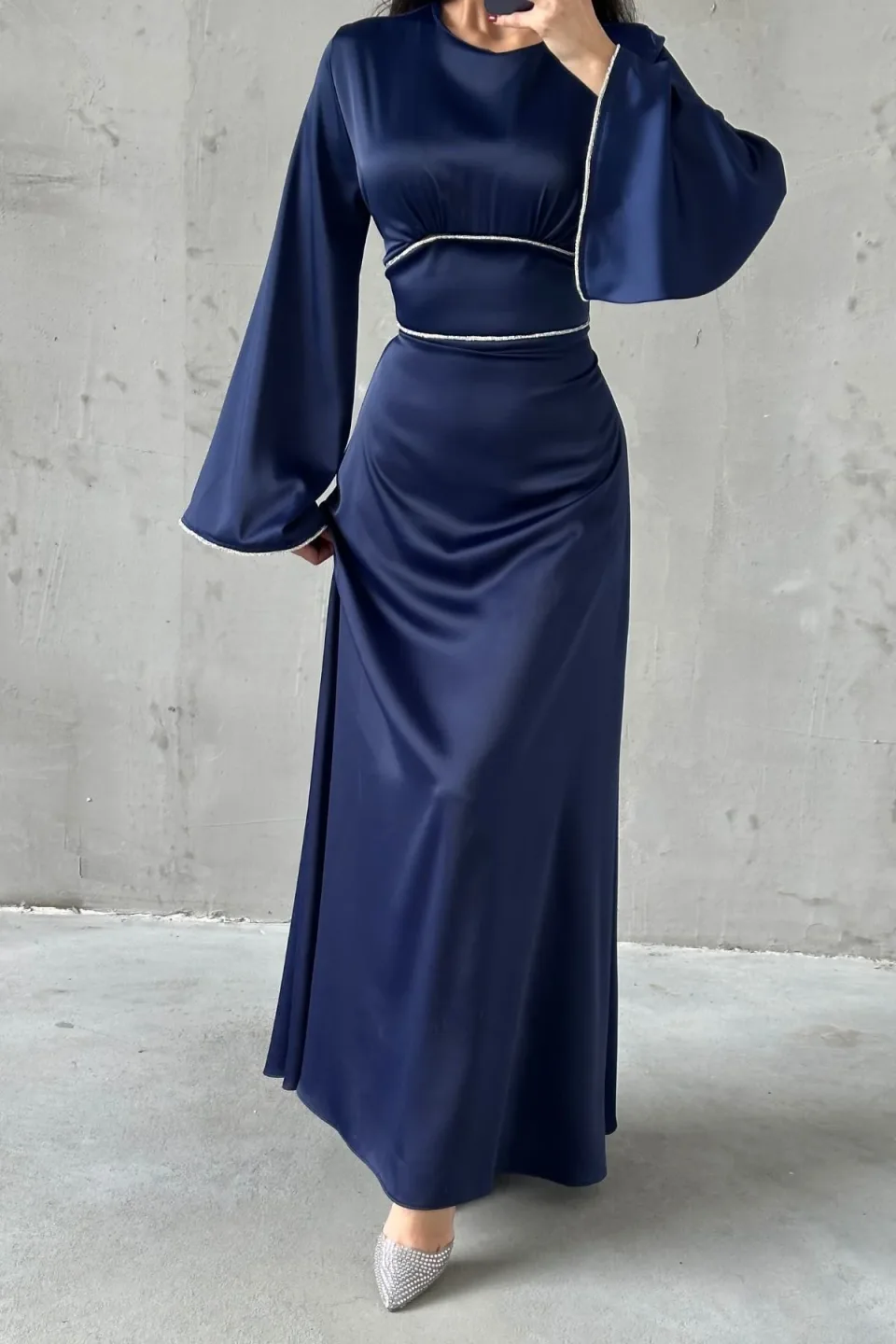 Navy blue maxi dress with wide, flowing sleeves and contrasting white trim along the neckline, waist, and cuffs. The dress is made of a smooth, draping fabric.