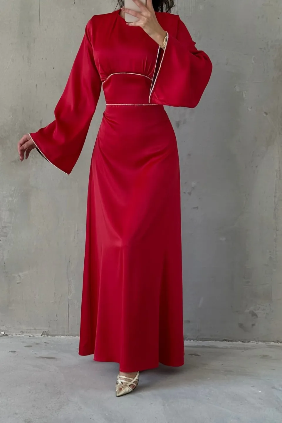 Red maxi dress with wide, flowing sleeves and contrasting white trim along the neckline, waist, and cuffs. The dress is made of a smooth, draping fabric.