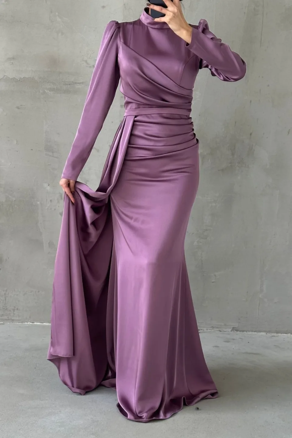 Elegant dusty rose formal dress with a flowing tail and refined hijab embellishments. The dress features a long, draped tail and detailed embellishments around the hijab area.