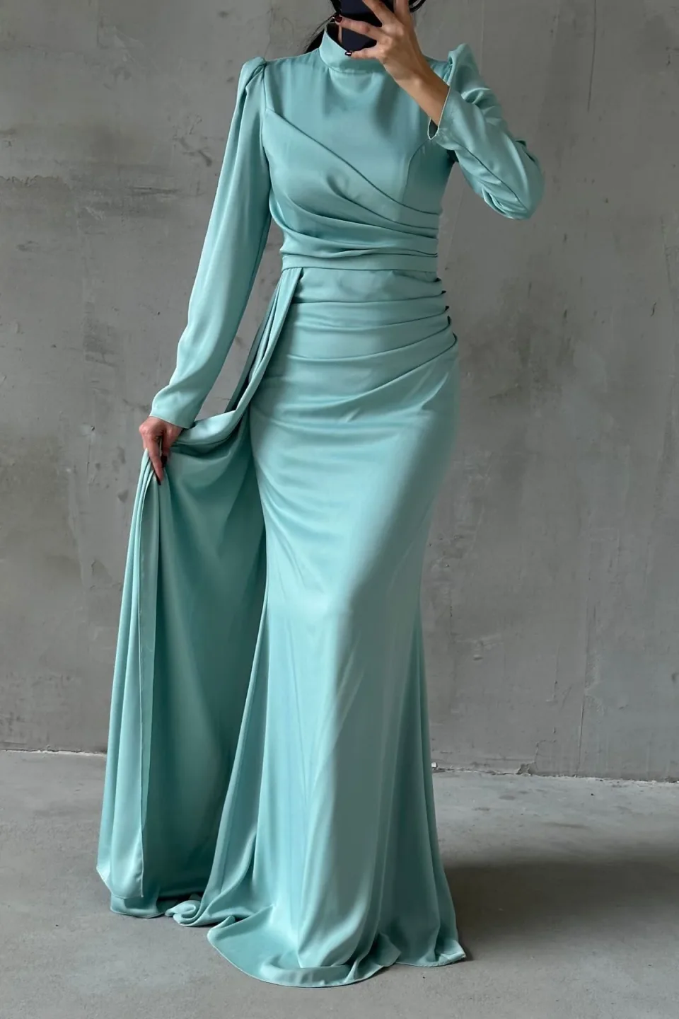 Elegant aqua green formal dress with a flowing tail and refined hijab embellishments. The dress features a long, draped tail and detailed embellishments around the hijab area.